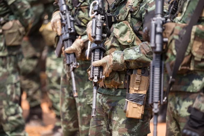 Soldados fardados segurando rifles em formação tática, representando o serviço militar obrigatório e questões de objeção de consciência.