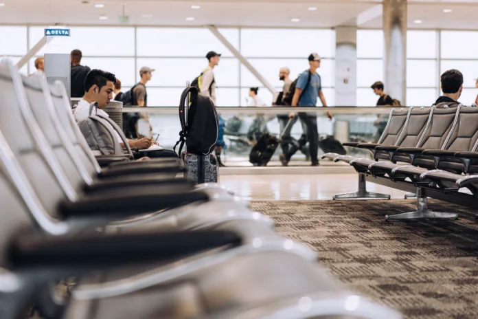 Passageiros aguardam em saguão de aeroporto, ilustrando atrasos e cancelamentos de voos. Cena representa transtornos enfrentados por viajantes devido a falhas na prestação de serviço aéreo.