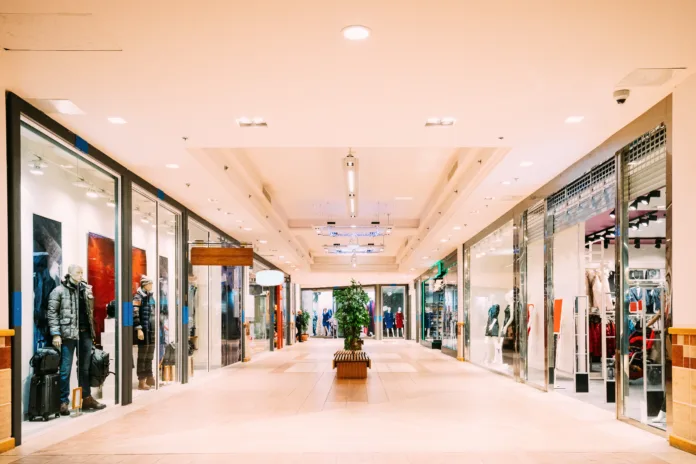 Corredor interno de um shopping center com vitrines de lojas de roupas e manequins, iluminado por luzes artificiais. Imagem ilustrativa para decisão do TST sobre creches em shoppings.